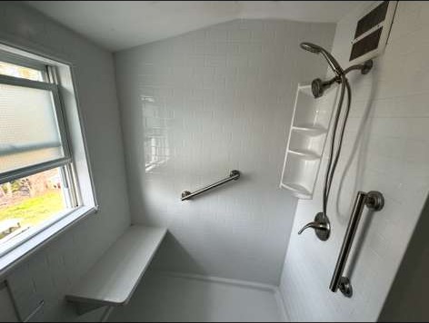 Curbless accessible shower with grab bars, bench and handheld shower head