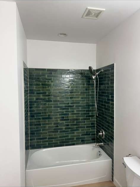 Bathroom tub surround with glossy green subway tile