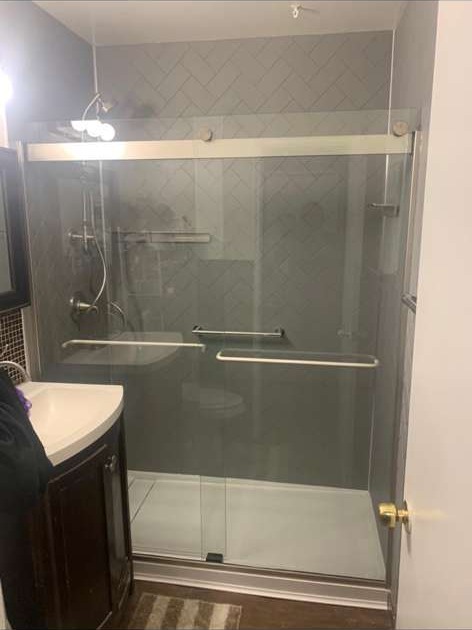 Bathroom shower with herringbone tile pattern and sliding glass door