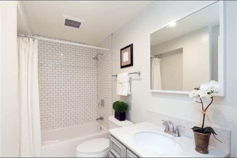 Finished bathroom with white subway tile tub surround and new vanity