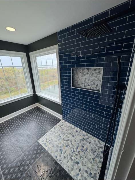Primary bathroom walk-in shower with navy subway tile, mosaic floor and matte black fixtures