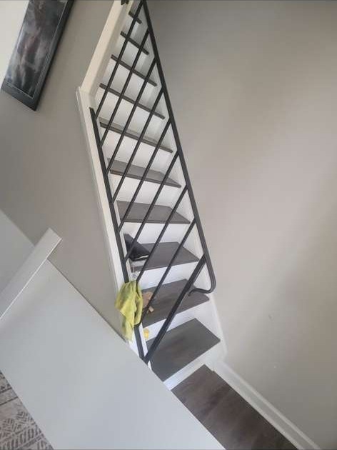 Remodeled staircase with black metal railing and hardwood treads